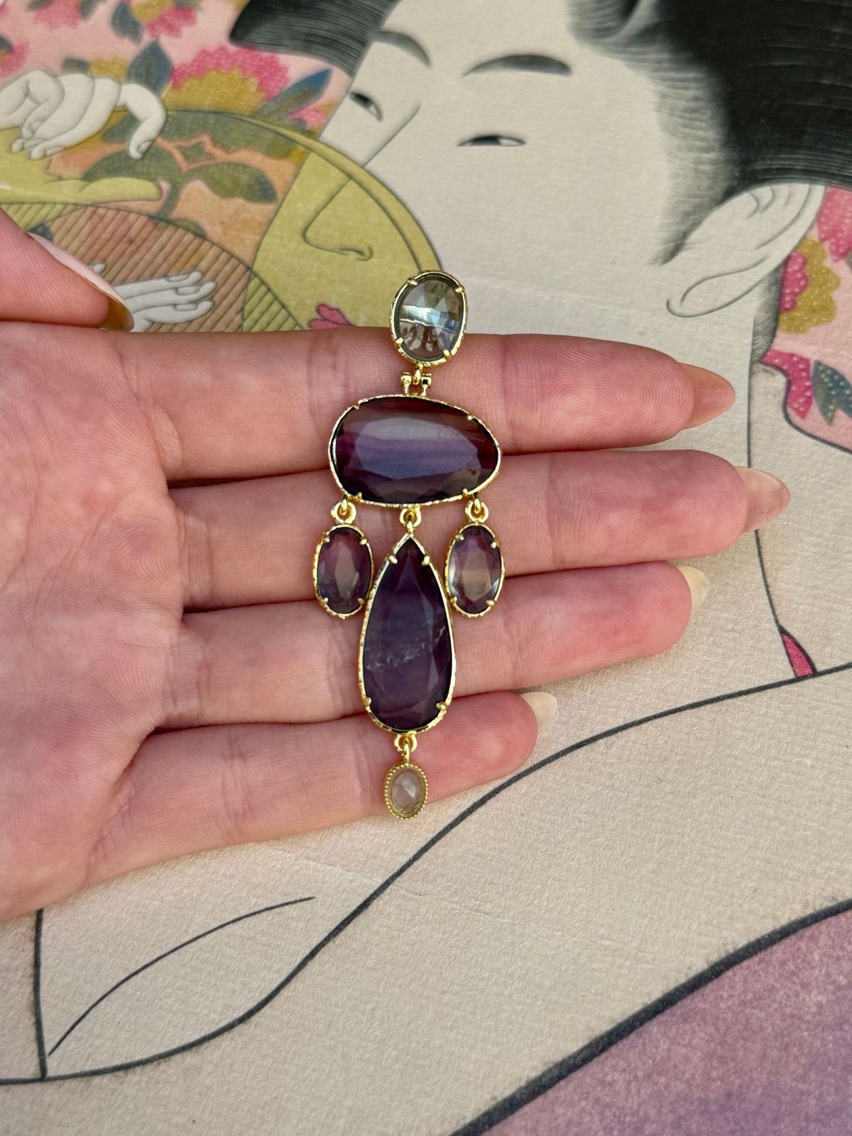 Taille d'une boucle d'oreille chandelier mauve posée dans la main