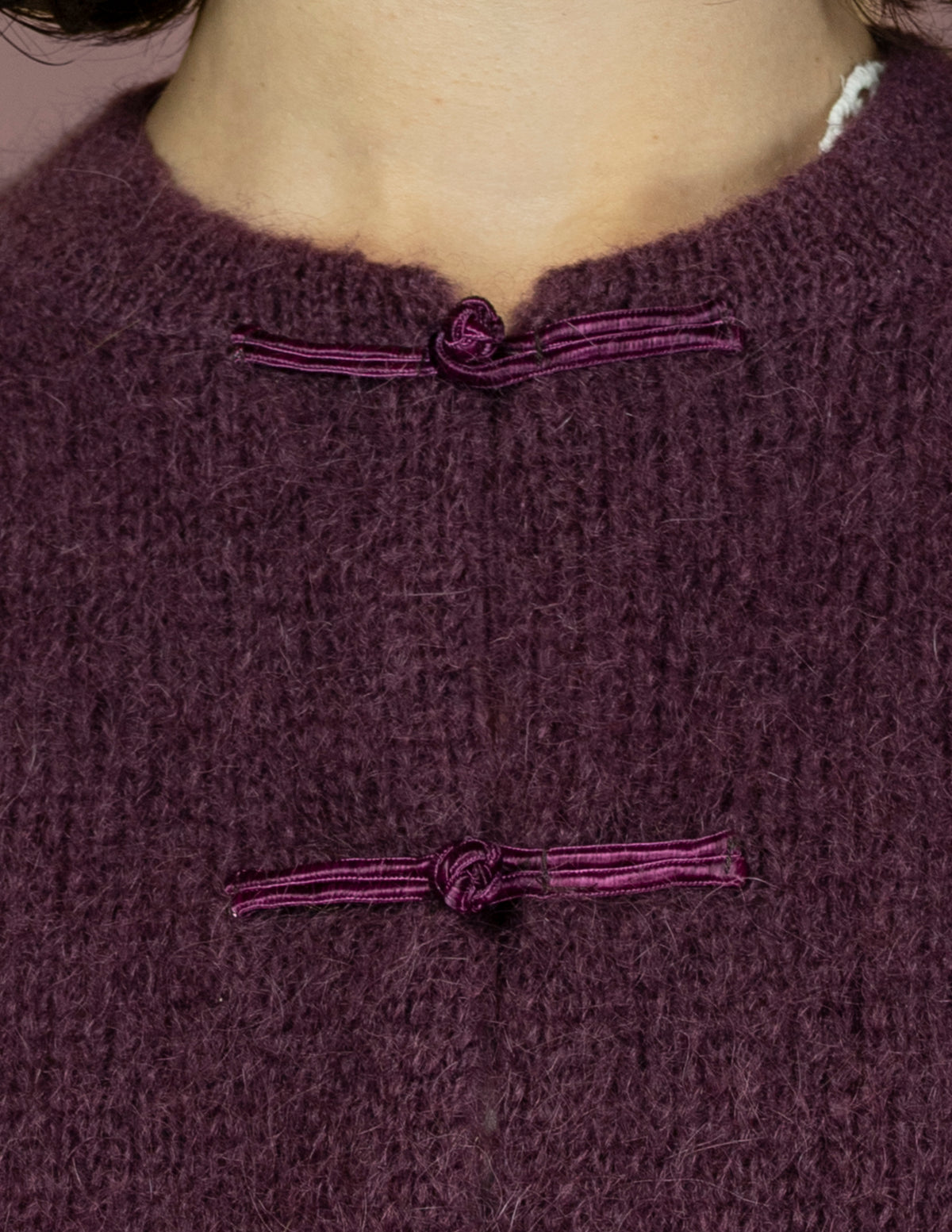 Détail de la maille duveteuse prune et des brandebourgs violine satinés