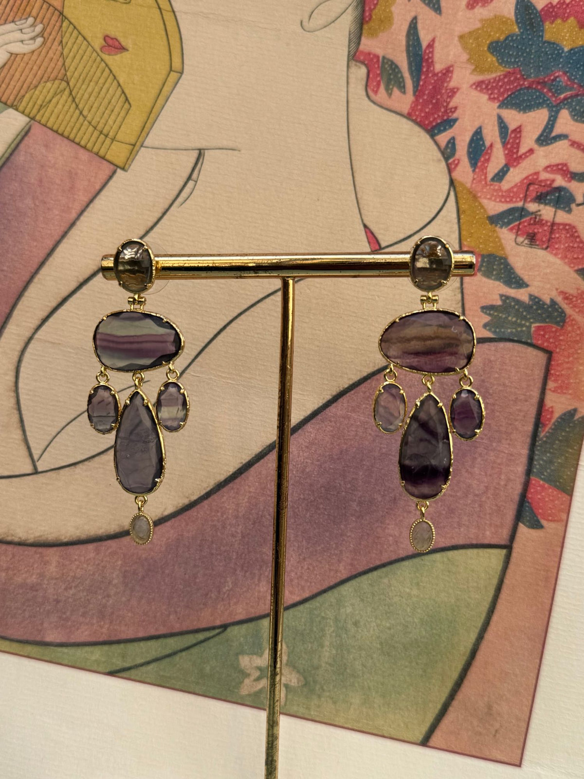 Paire de boucles d'oreilles pendantes chandelier mauves et bleues sur présentoir doré