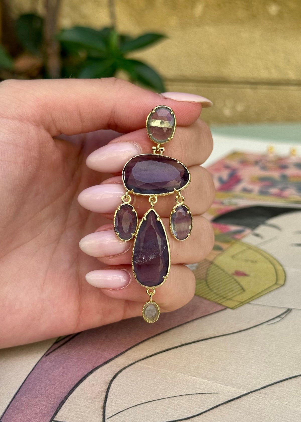 Boucle d'oreille pendante XXL à pierres mauves tenue en main