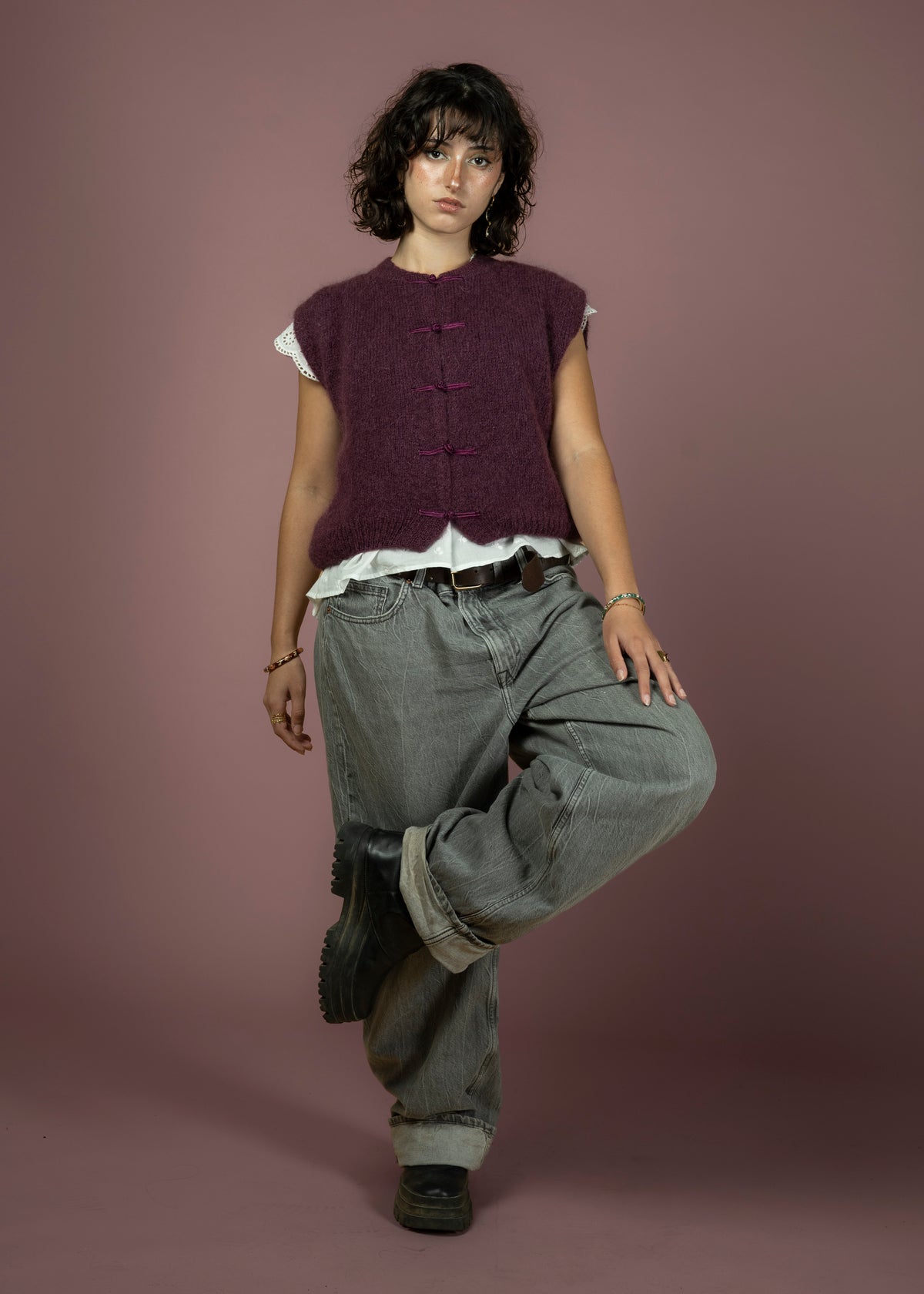 Gilet sans manches violet porté sur une blouse blanche avec un jean gris large